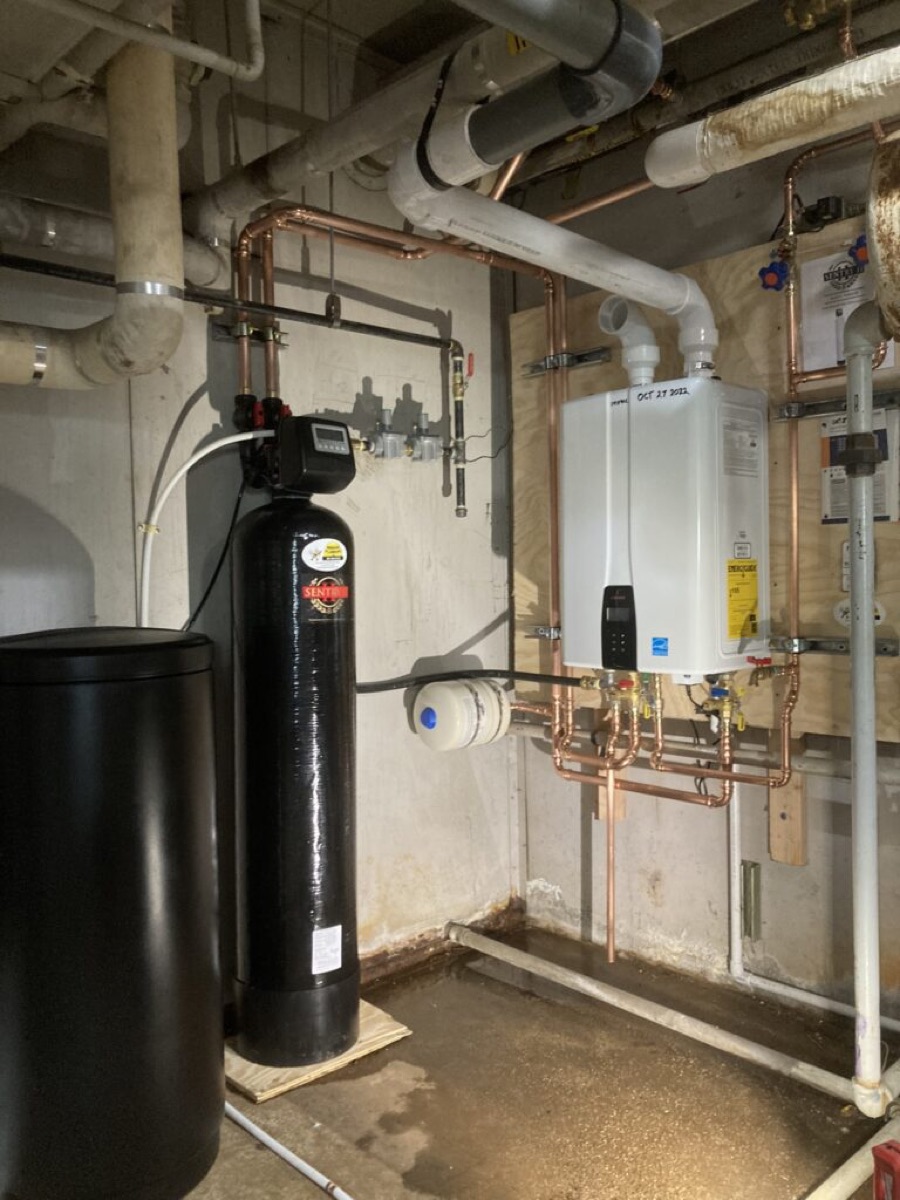Wall-mounted tankless water heater installed alongside a water softener