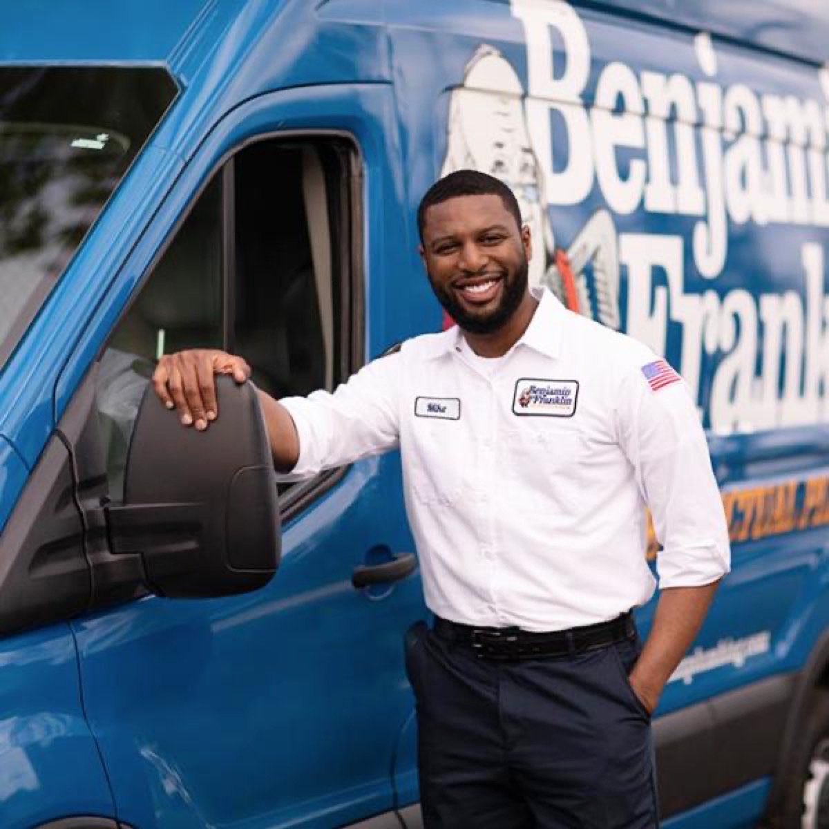 Benjamin Franklin plumber standing beside a branded service van