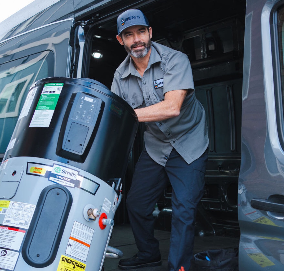Ben's Plumbing plumber unloading a new water heater from a company van