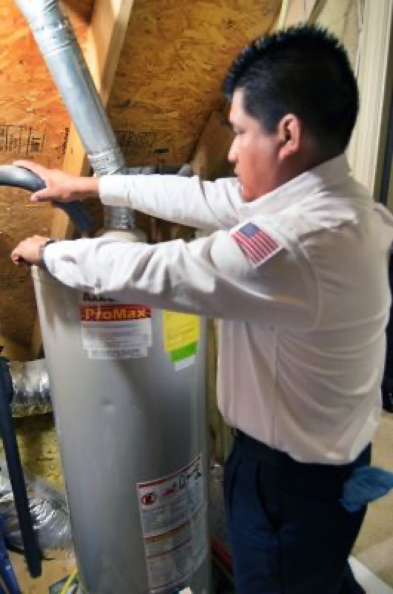 Berkeys technician working on a gas tank water heater in an attic