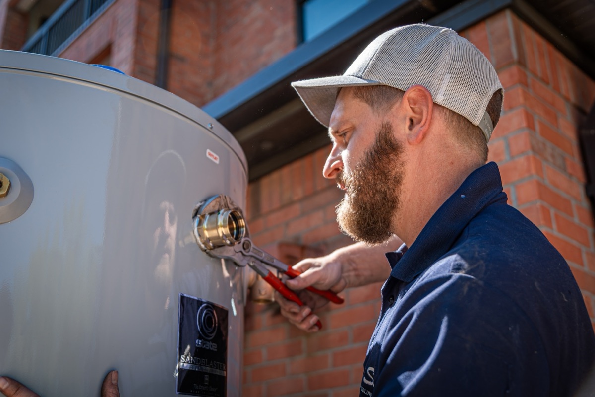 Blue Sky technician working on a tank water heater's fittings