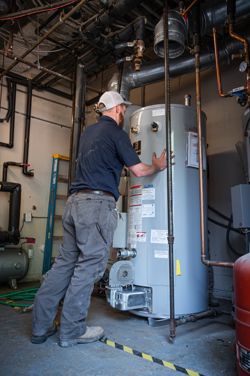 Blue Sky technician checking an installed tank water heater in a mechanical room