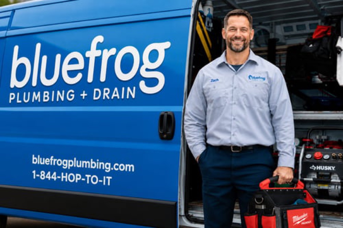 Plumber beside a bluefrog service van