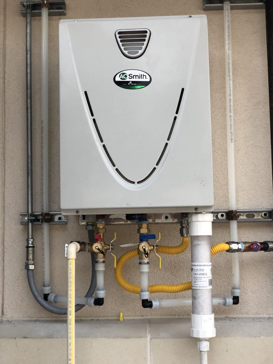 Wall-mounted tankless water heater installation with gas and water connections