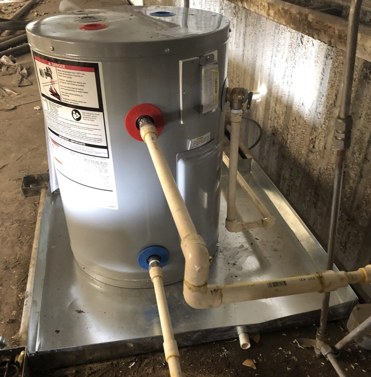 Electric tank water heater installed in a drain pan