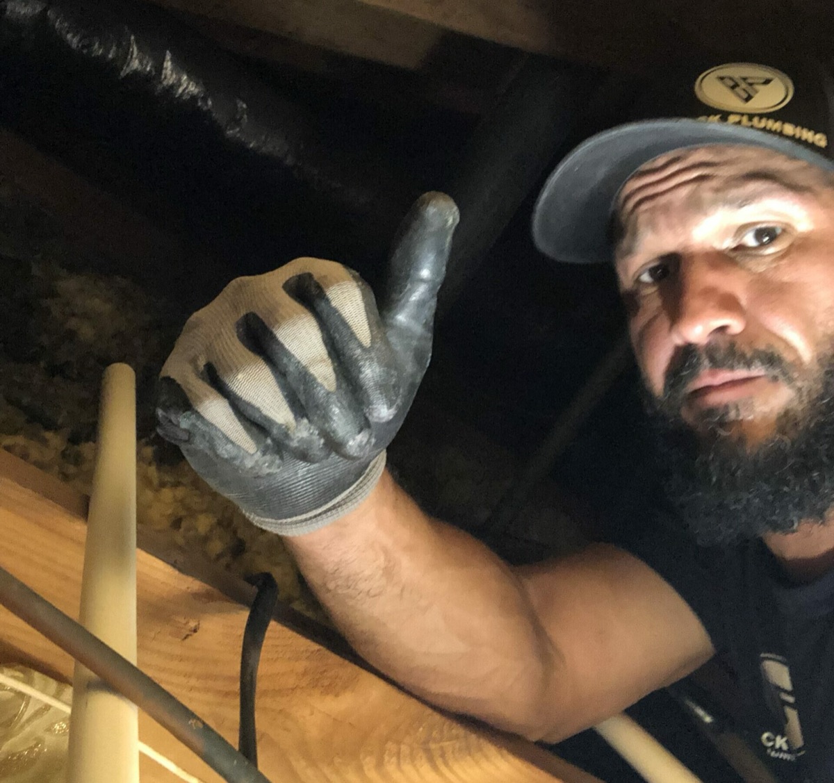 Brick Plumbing plumber giving a thumbs-up while working in an attic