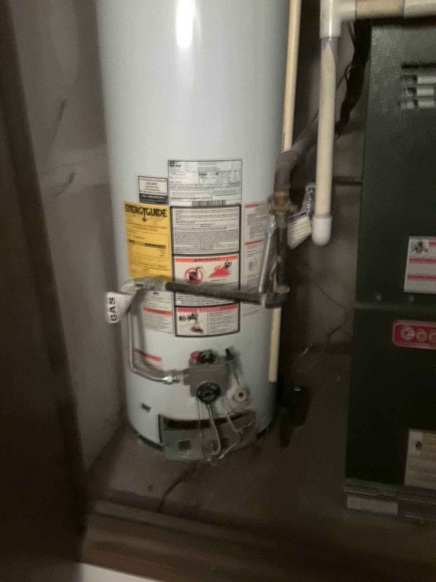 White gas tank water heater installed next to a furnace