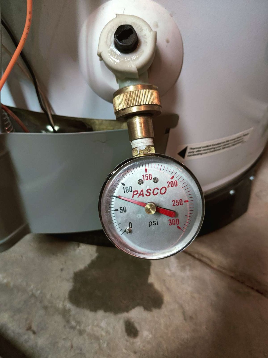 Pressure gauge attached to a tank water heater fitting during service