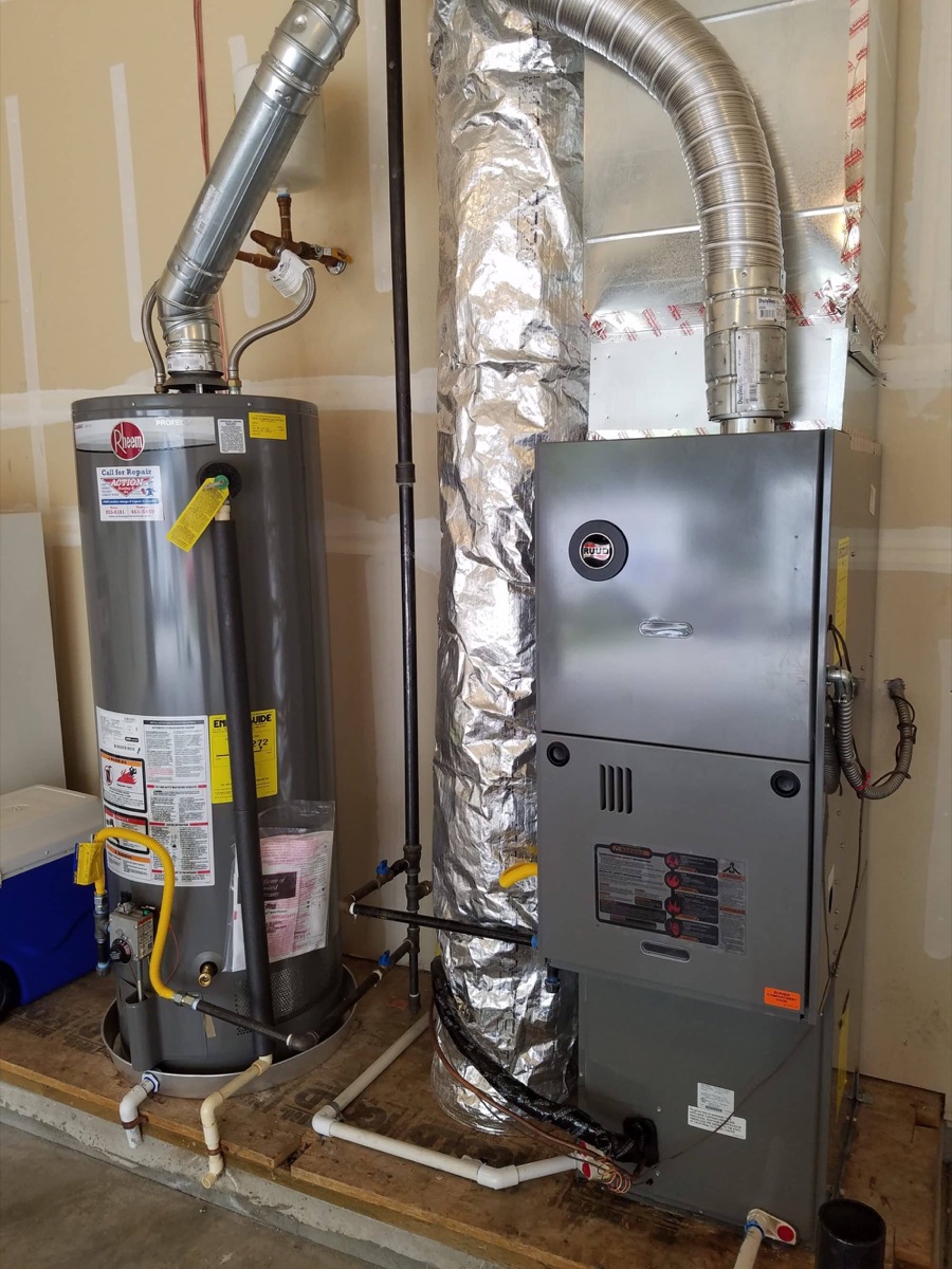 Installed gas tank water heater beside a new furnace in a garage/utility space