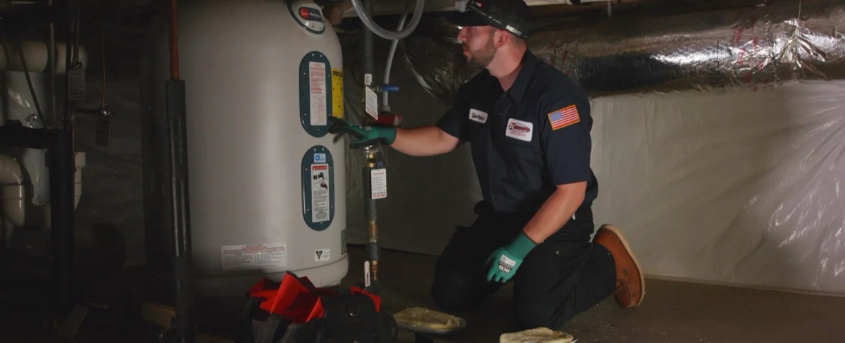 CM Heating technician working on a water heater in a basement