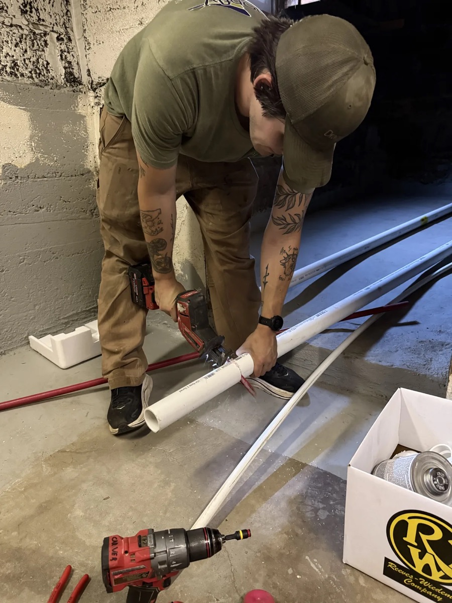 Dragonfly technician cutting PVC vent pipe for a tankless water heater installation