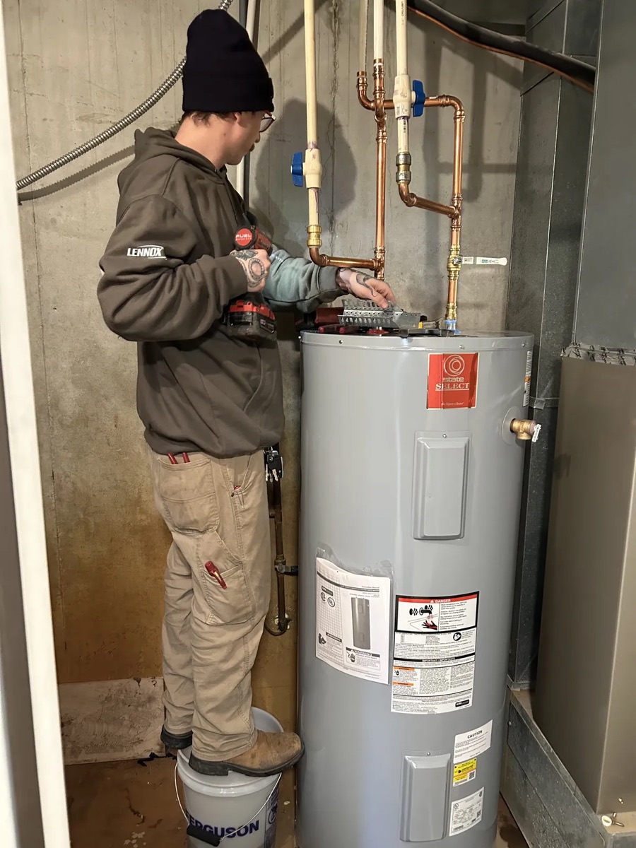 Technician making up the copper connections on a newly installed electric tank water heater