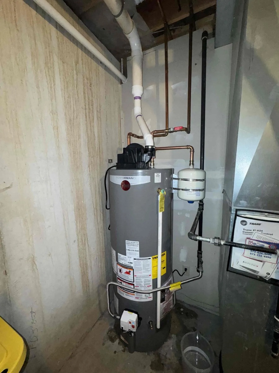 Gas water heater with a thermal expansion tank fitted above it in a crawlspace