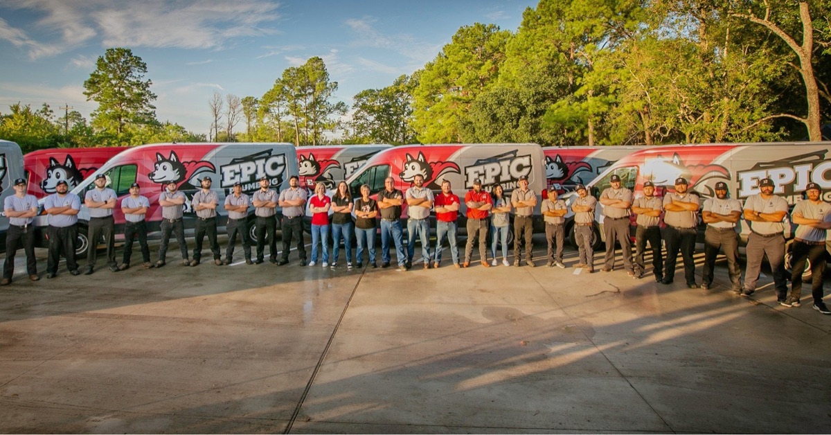 Epic Plumbing team lined up in front of a row of company vans