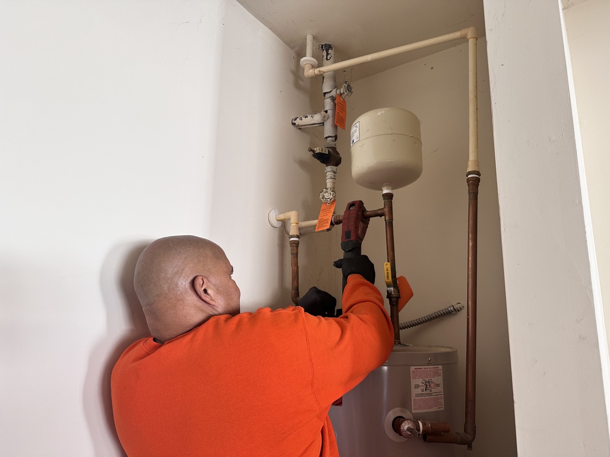 Estes technician working on water heater piping