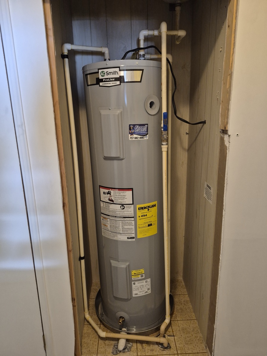 New A.O. Smith ProLine electric tank water heater installed in a closet, bearing a Farrell Plumbing sticker