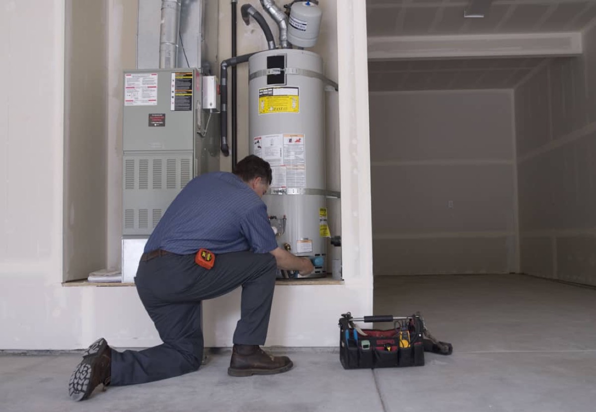 Fast Water Heater technician servicing a tank water heater in a garage (company photo)