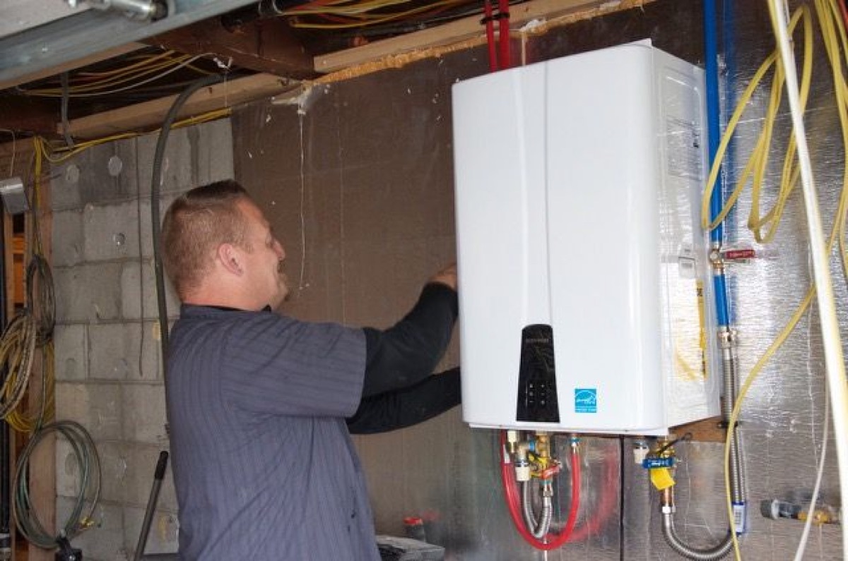 Green Planet technician working on a wall-mounted tankless water heater
