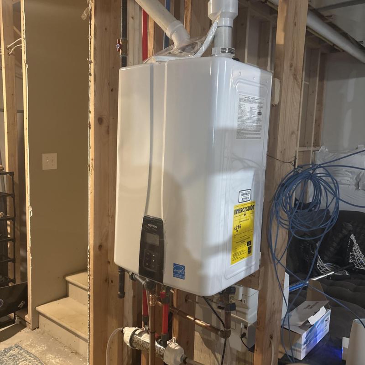 Wall-mounted tankless water heater installed in an unfinished basement