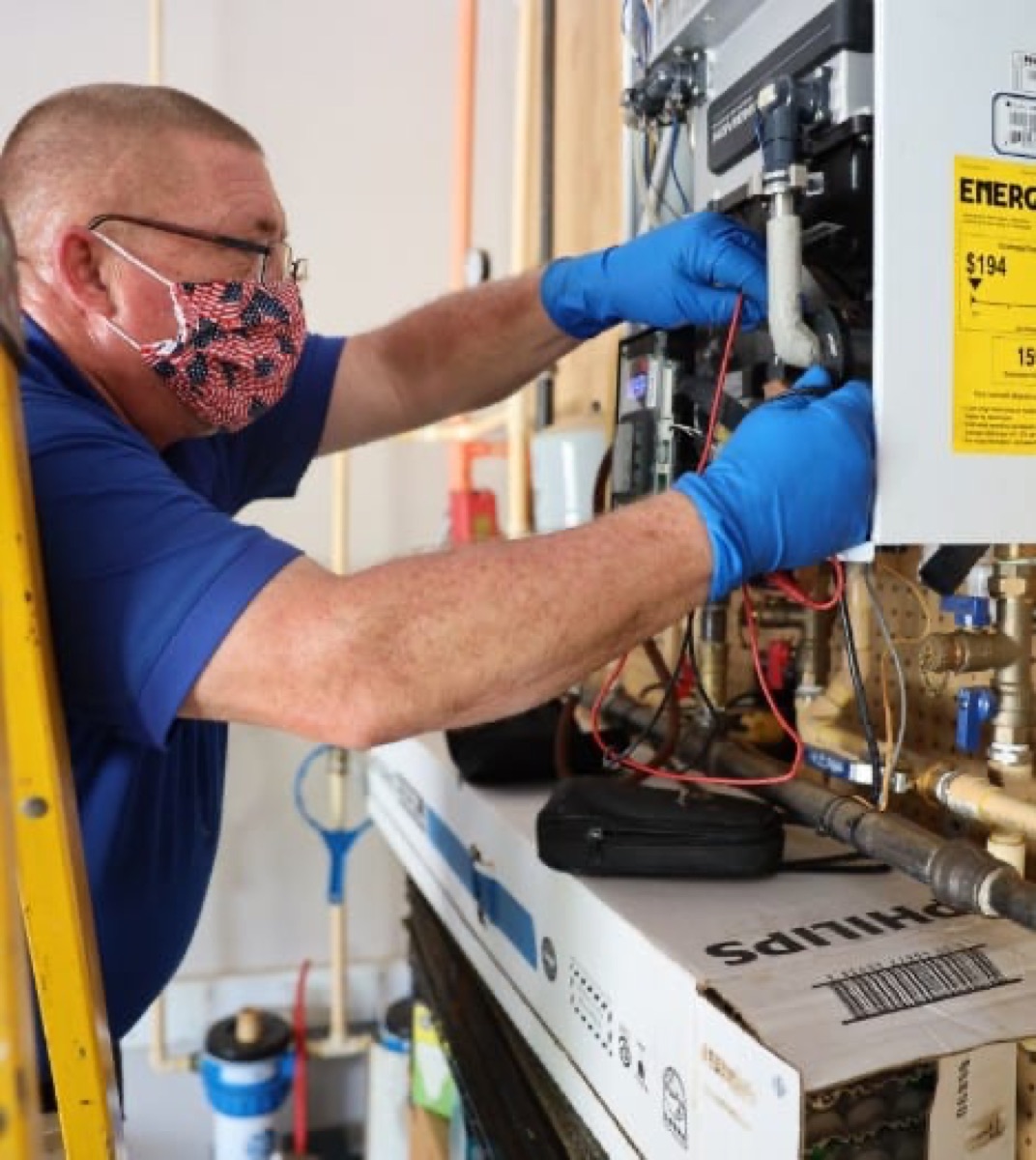 Modern Plumbing technician performing maintenance on a wall-mounted tankless water heater