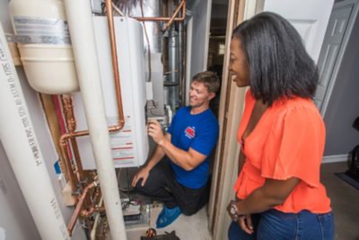 Mr. Plumber technician with a tankless water heater and customer