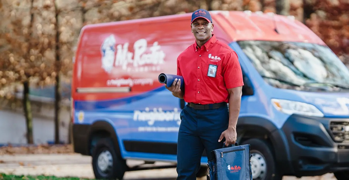 Mr. Rooter employee standing beside a branded work van