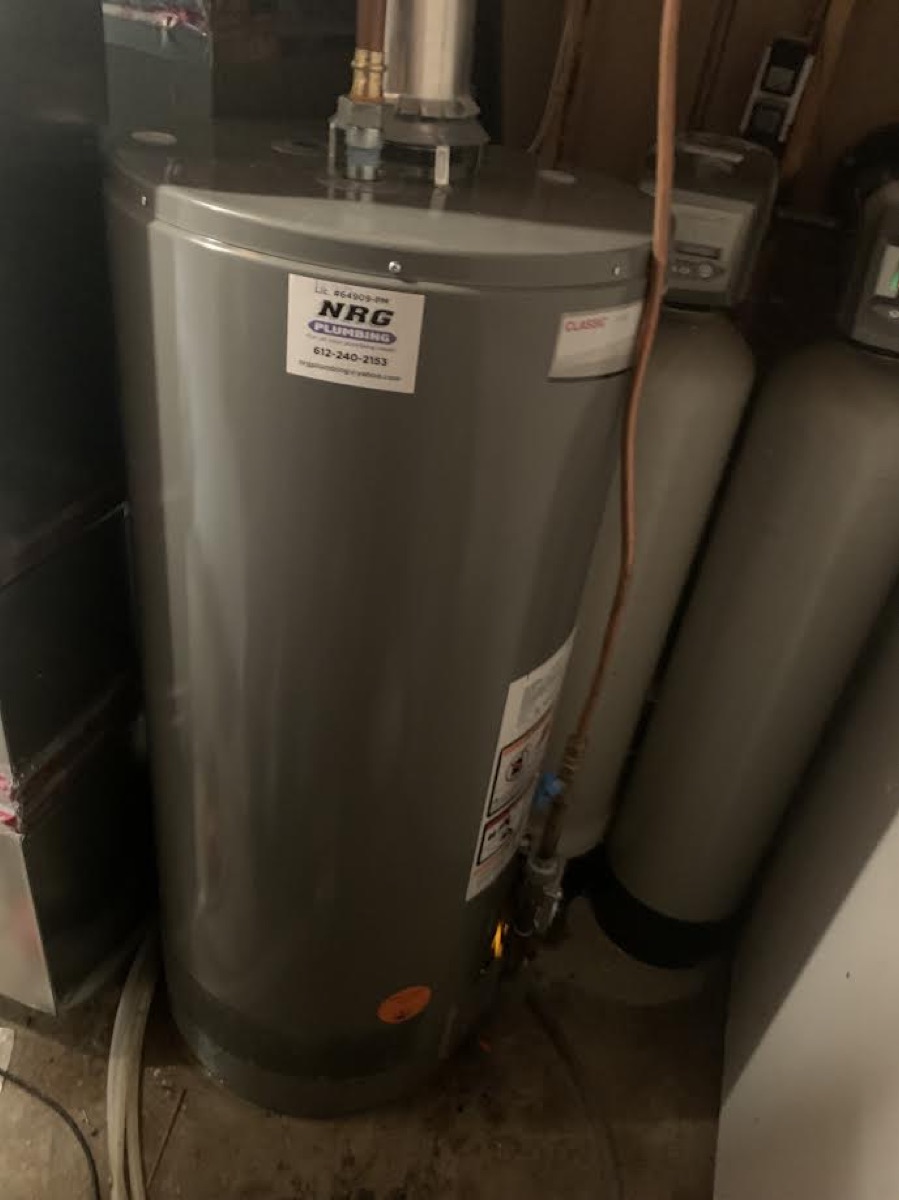 Gray tank water heater with NRG sticker beside water-softener tanks