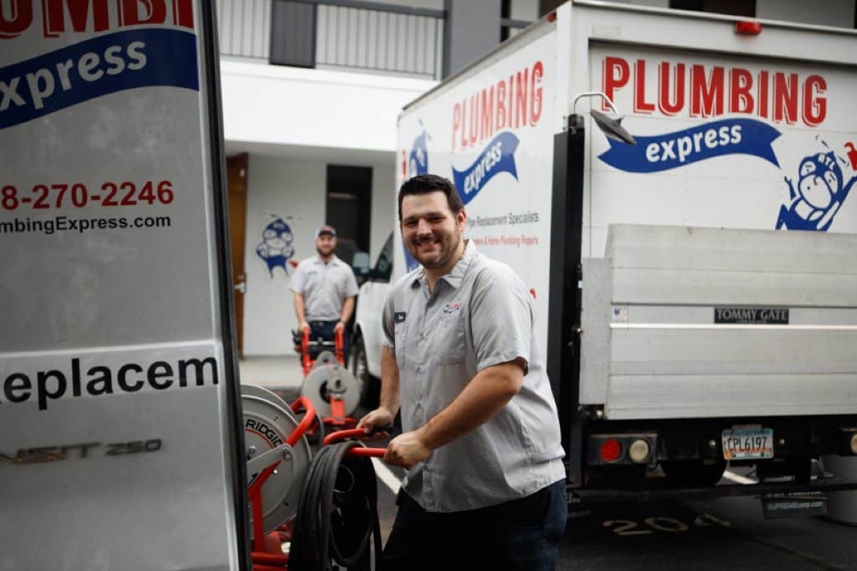 Plumbing Express technician with equipment at the back of a branded box truck