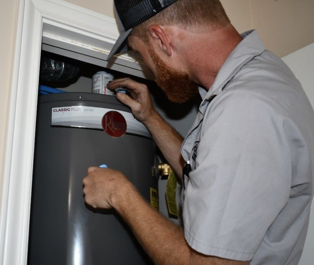 Plumber repairing water heater in a closet at a residential property