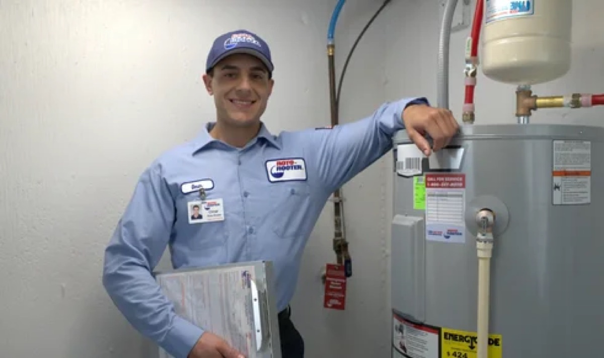 Roto-Rooter technician standing beside a tank water heater