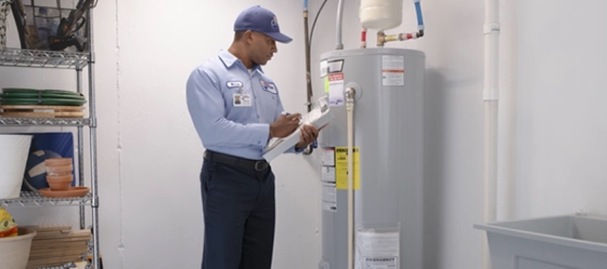 Roto-Rooter technician with a clipboard inspecting a tank water heater