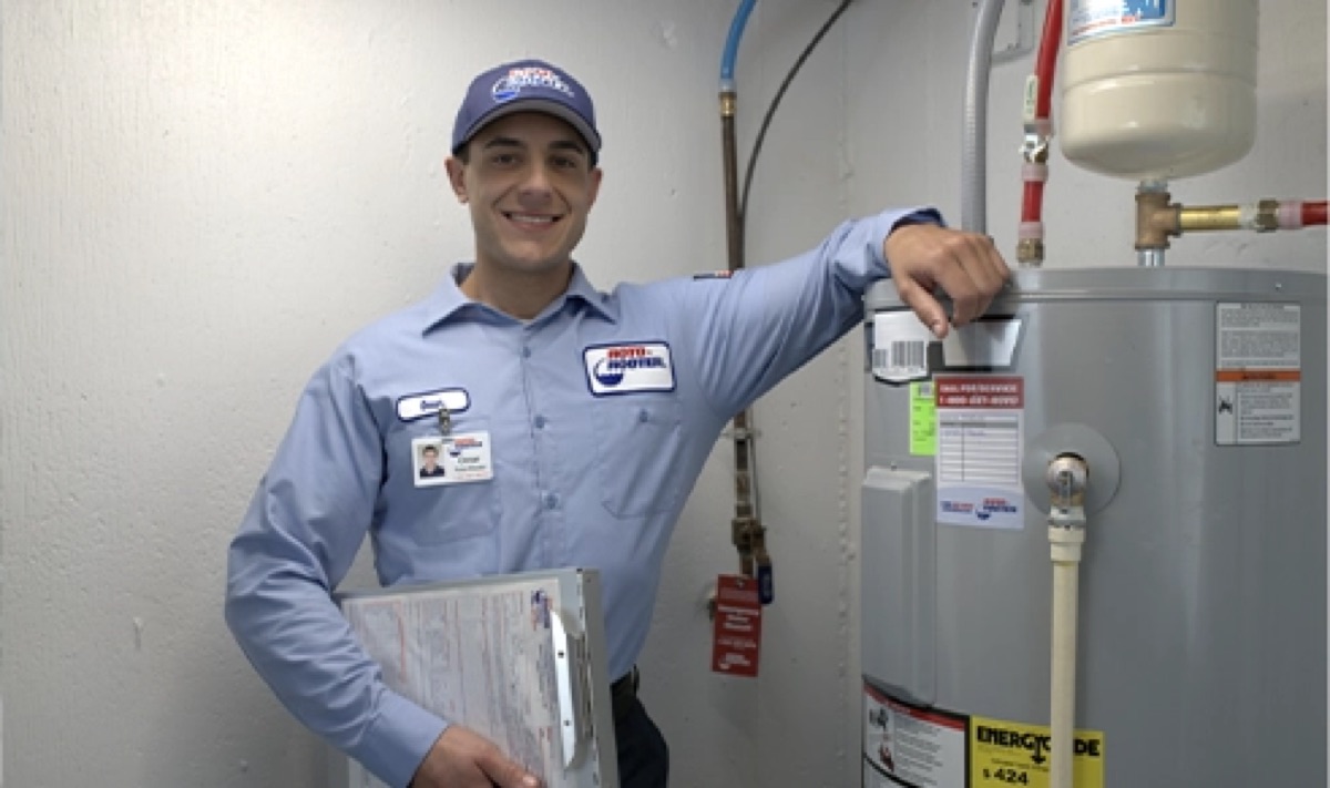 Roto-Rooter technician standing beside a tank water heater