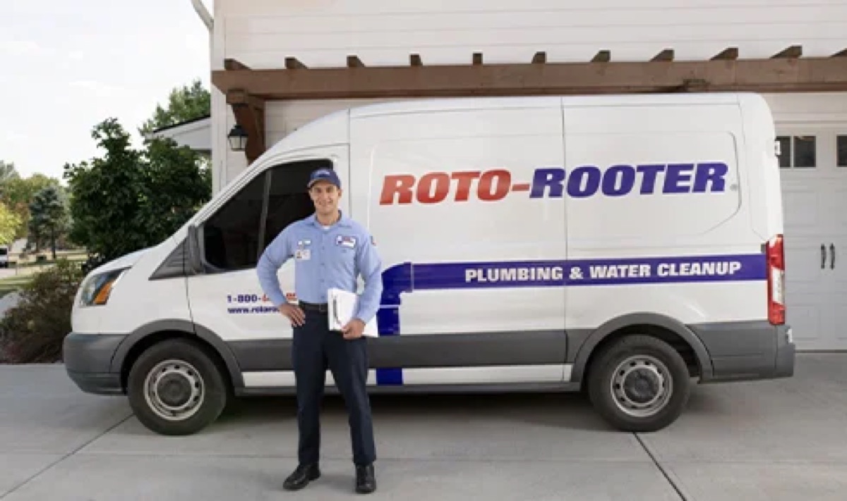Roto-Rooter technician standing in front of a branded service van