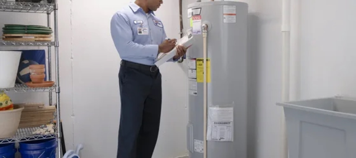 Roto-Rooter technician with a clipboard inspecting a tank water heater