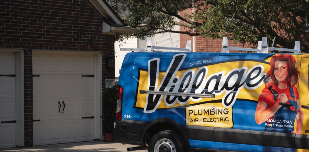 Village Plumbing, Air & Electric service van parked outside a brick home