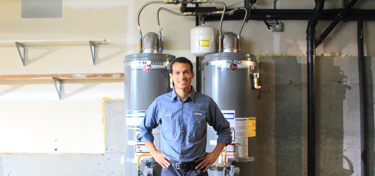 Technician in front of two installed tank water heaters