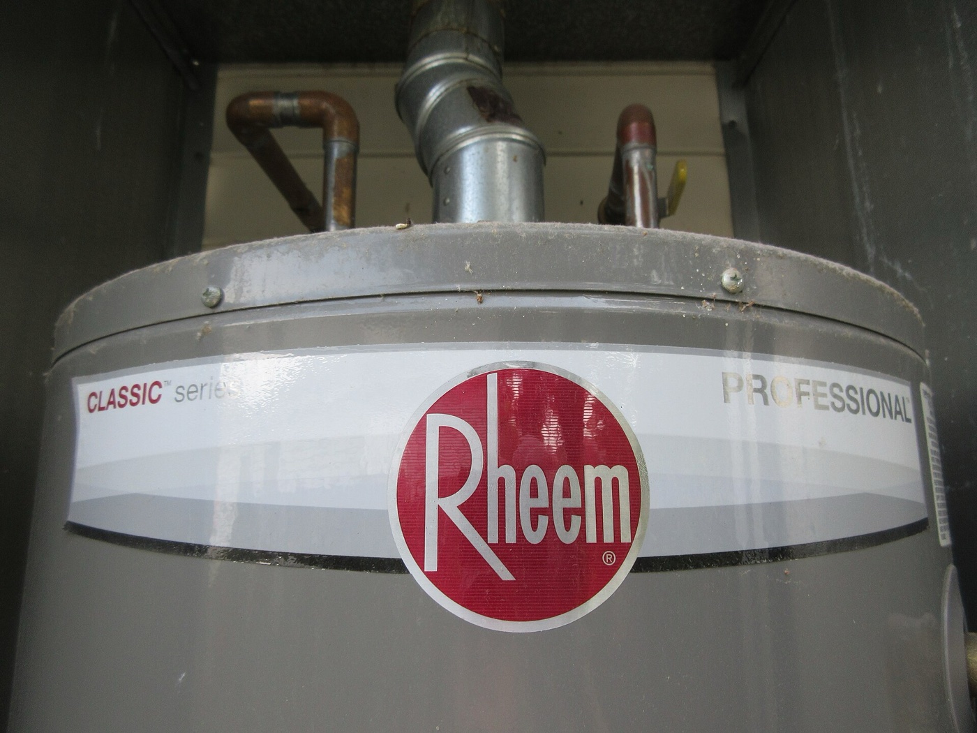 Top of a gas tank water heater showing the metal flue vent pipe and hot and cold water connections