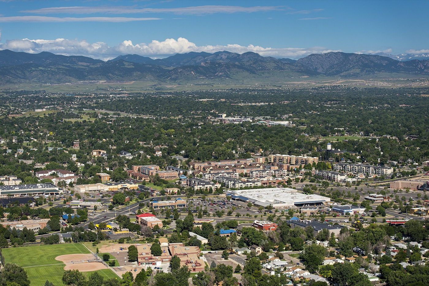 Aerial view of tree-lined Arvada neighborhoods stretching toward the Rocky Mountain foothills