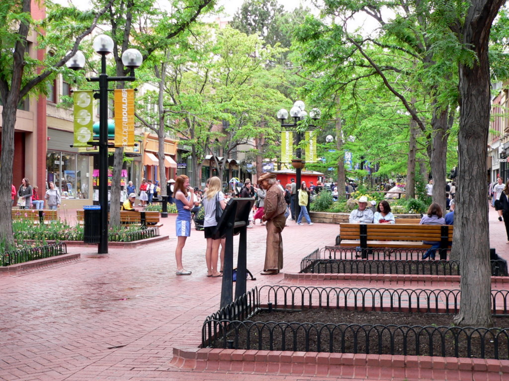 Tree-shaded brick pedestrian mall with lampposts and storefronts on Pearl Street in downtown Boulder