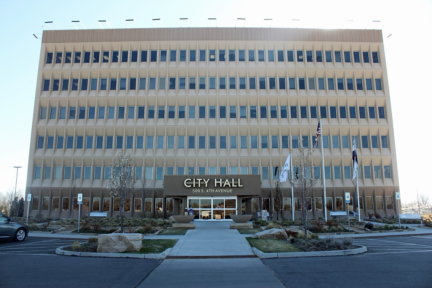 Multi-story Brighton City Hall building with flagpoles and landscaped plaza