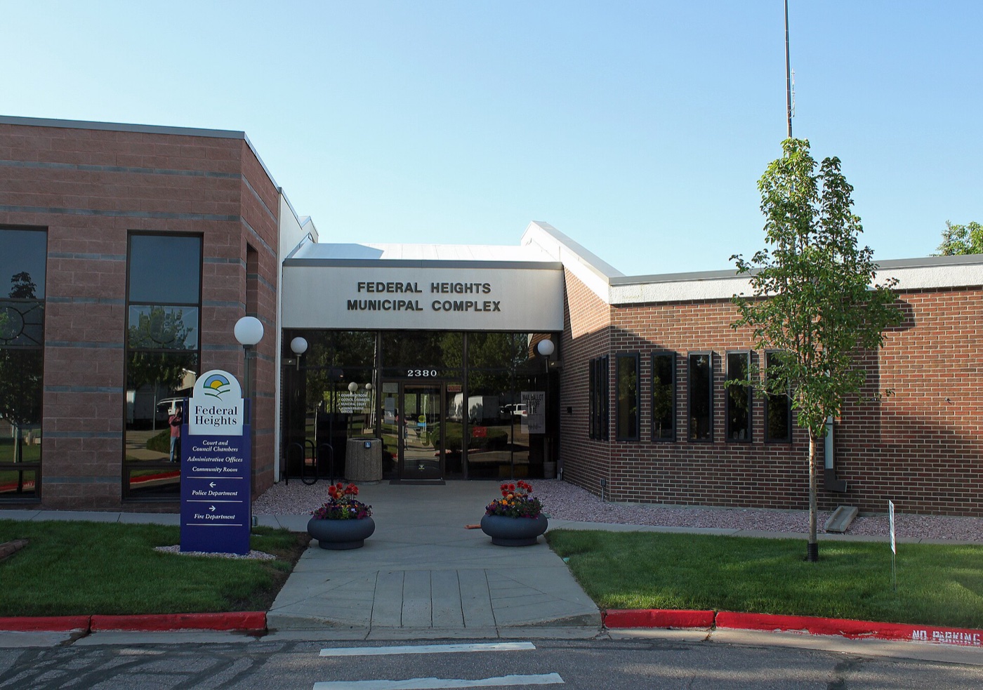 Brick Federal Heights Municipal Complex entrance with planters and trees