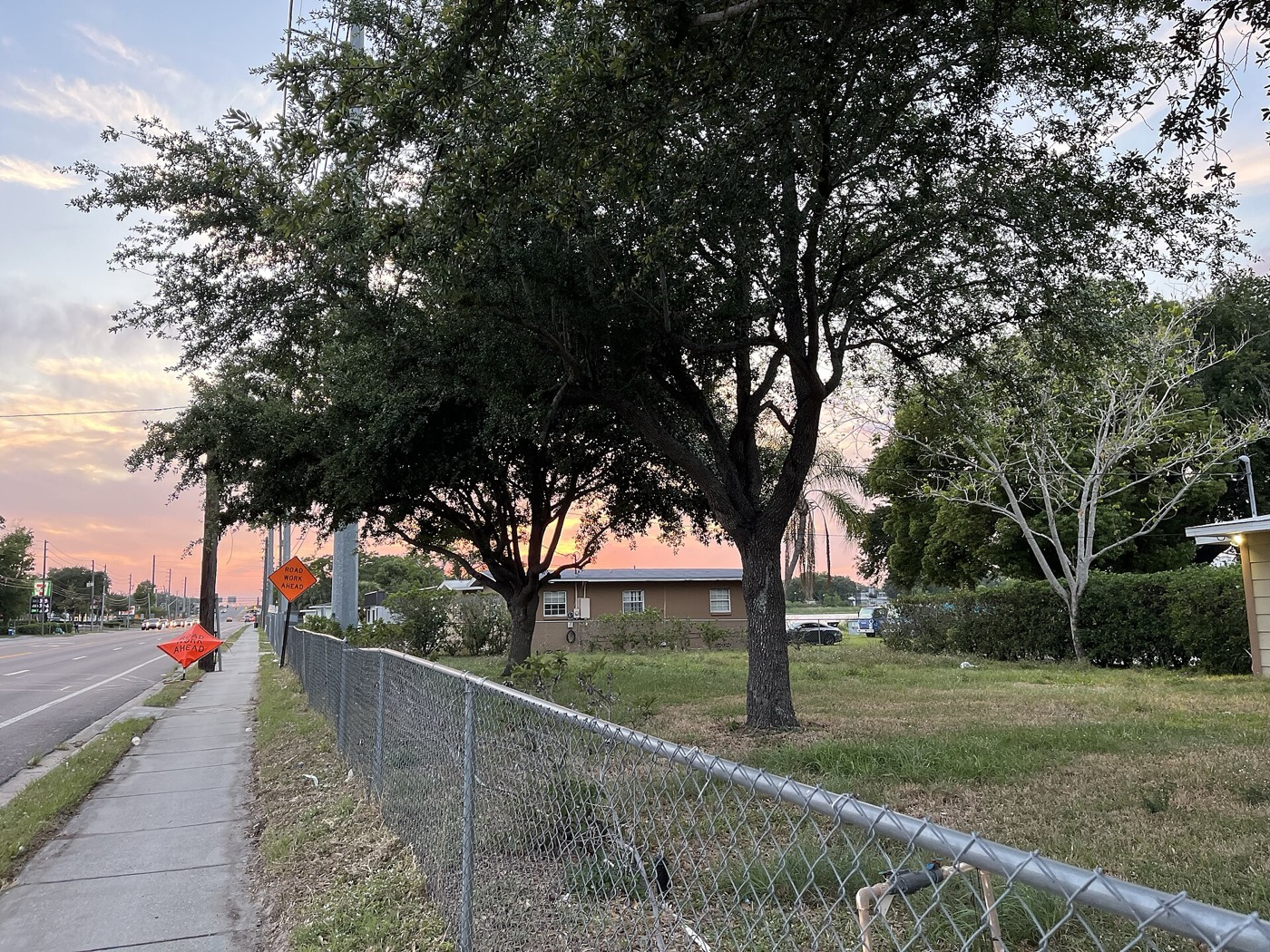 Trees and a sidewalk along a road in Pine Castle at dusk