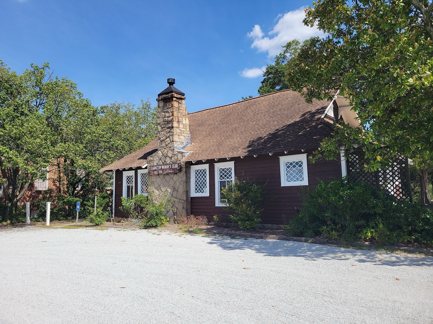 Small historic Clarkston Woman's Club building with a stone chimney among trees