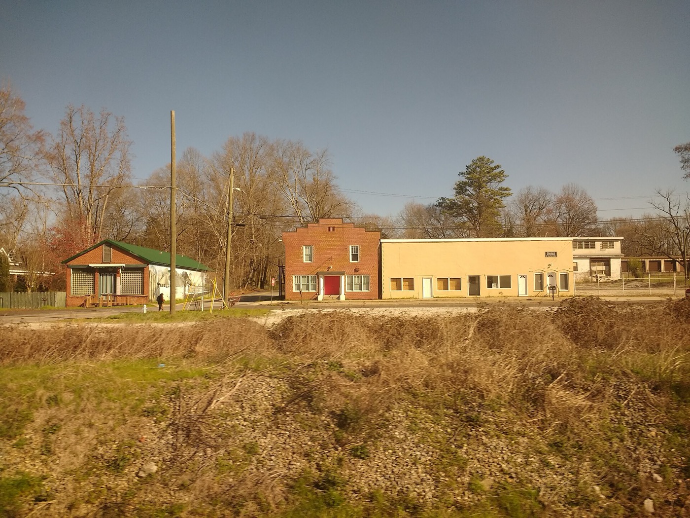 A small house and brick commercial buildings along a road in Mableton, Georgia