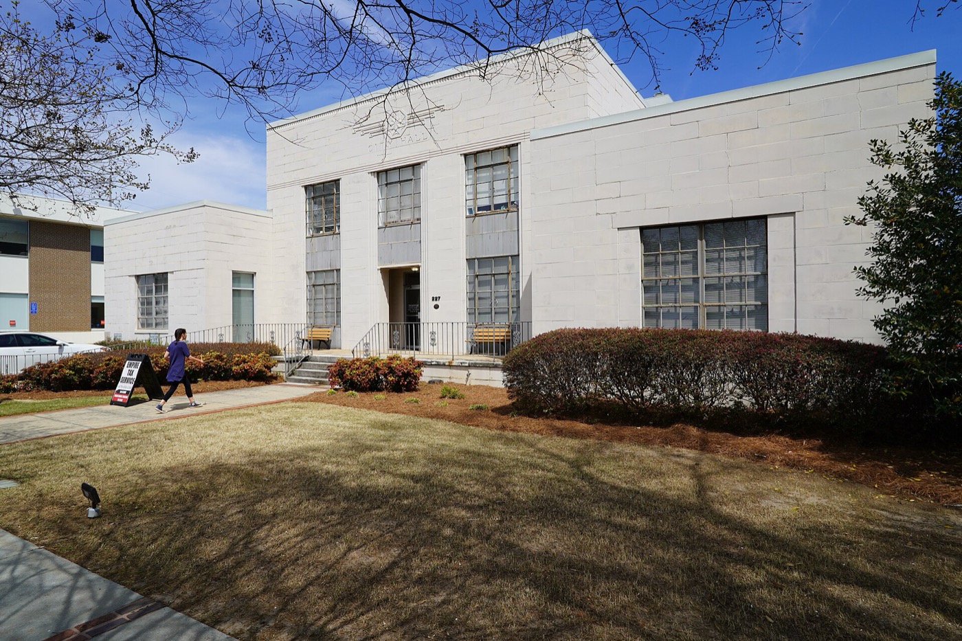 White two-story Monroe City Hall building with a lawn and shrubs