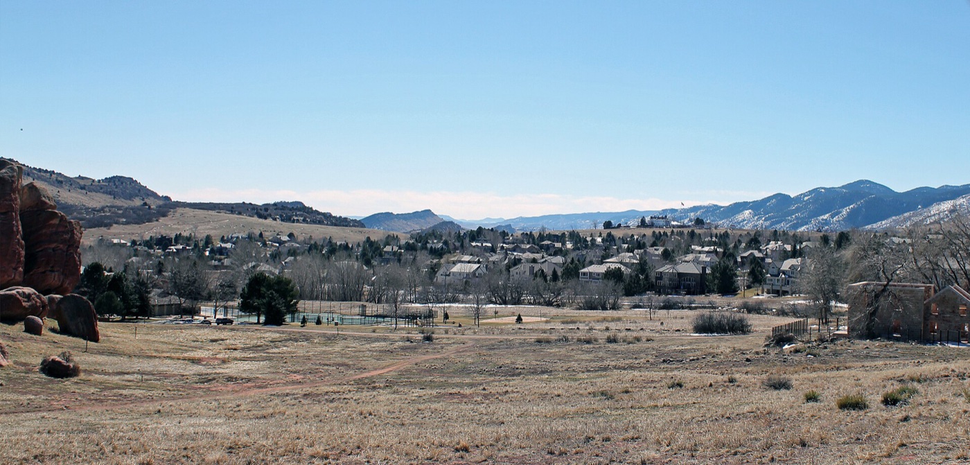 Open grassland in front of Ken Caryl homes with red-rock foothills behind