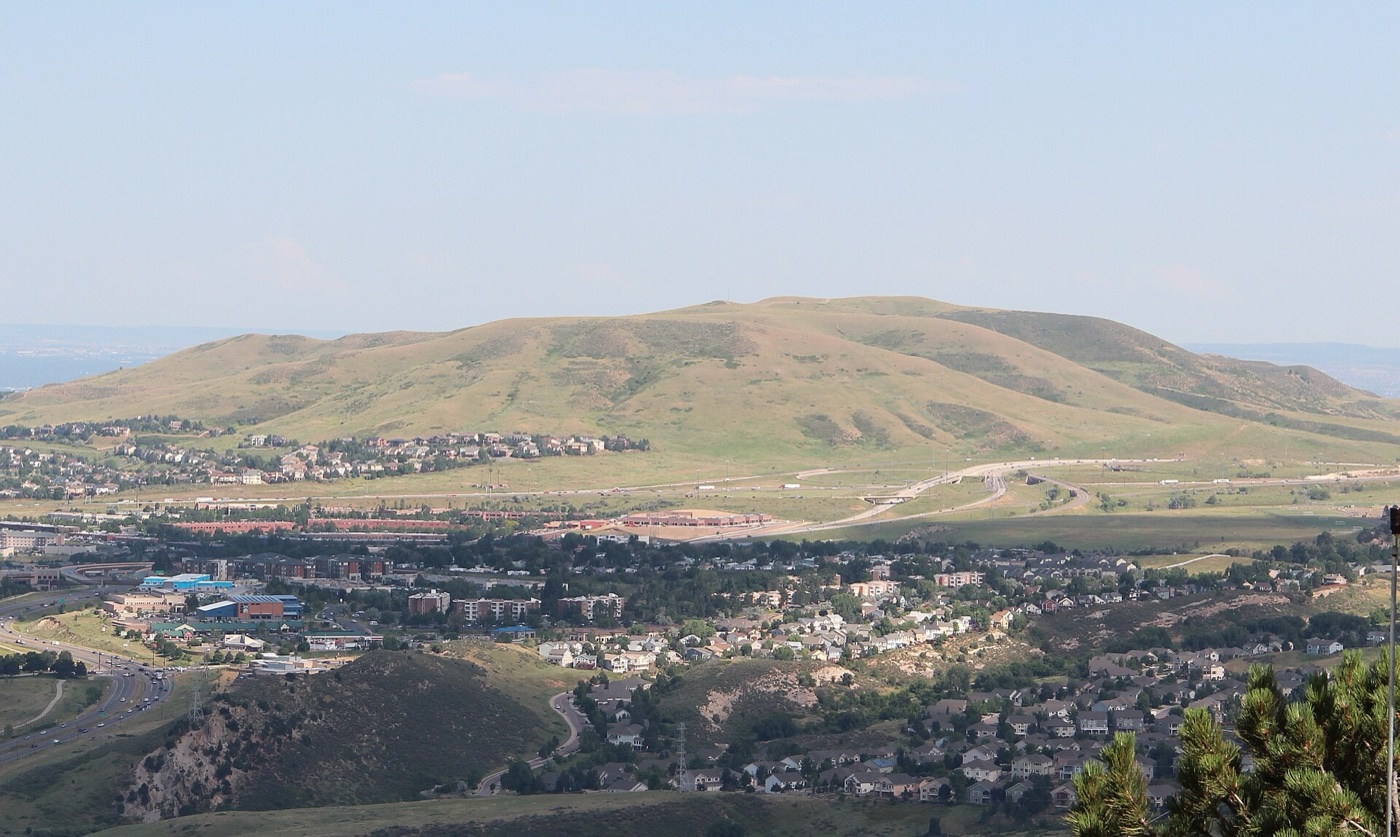 Grassy Green Mountain rising above rooftops of Lakewood neighborhoods