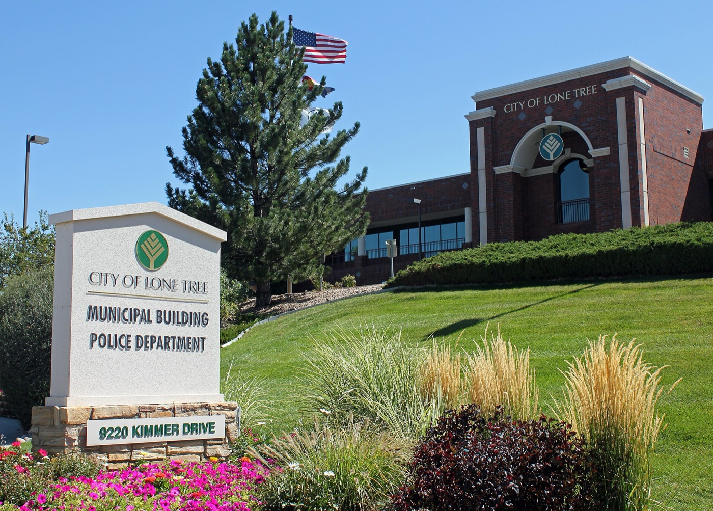 Brick Lone Tree municipal building with landscaped entry sign and flag