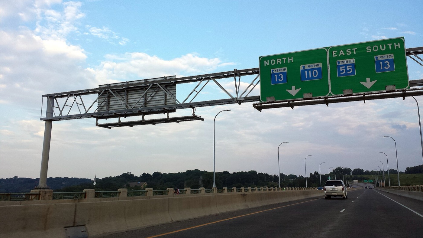 Overhead highway signs for Minnesota Highways 13, 110 and 55 above a bridge roadway at Mendota Heights