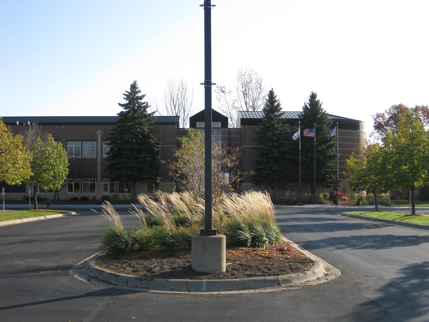 Brick Woodbury City Hall building behind evergreens and a landscaped traffic island